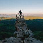 man holding bike while standing on gray mountain
