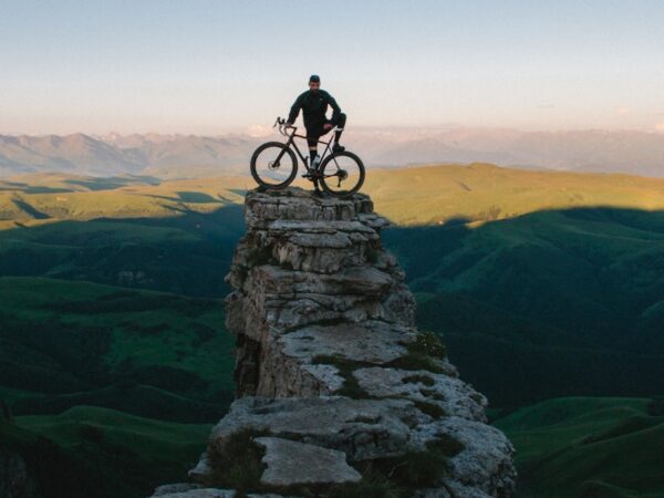 man holding bike while standing on gray mountain
